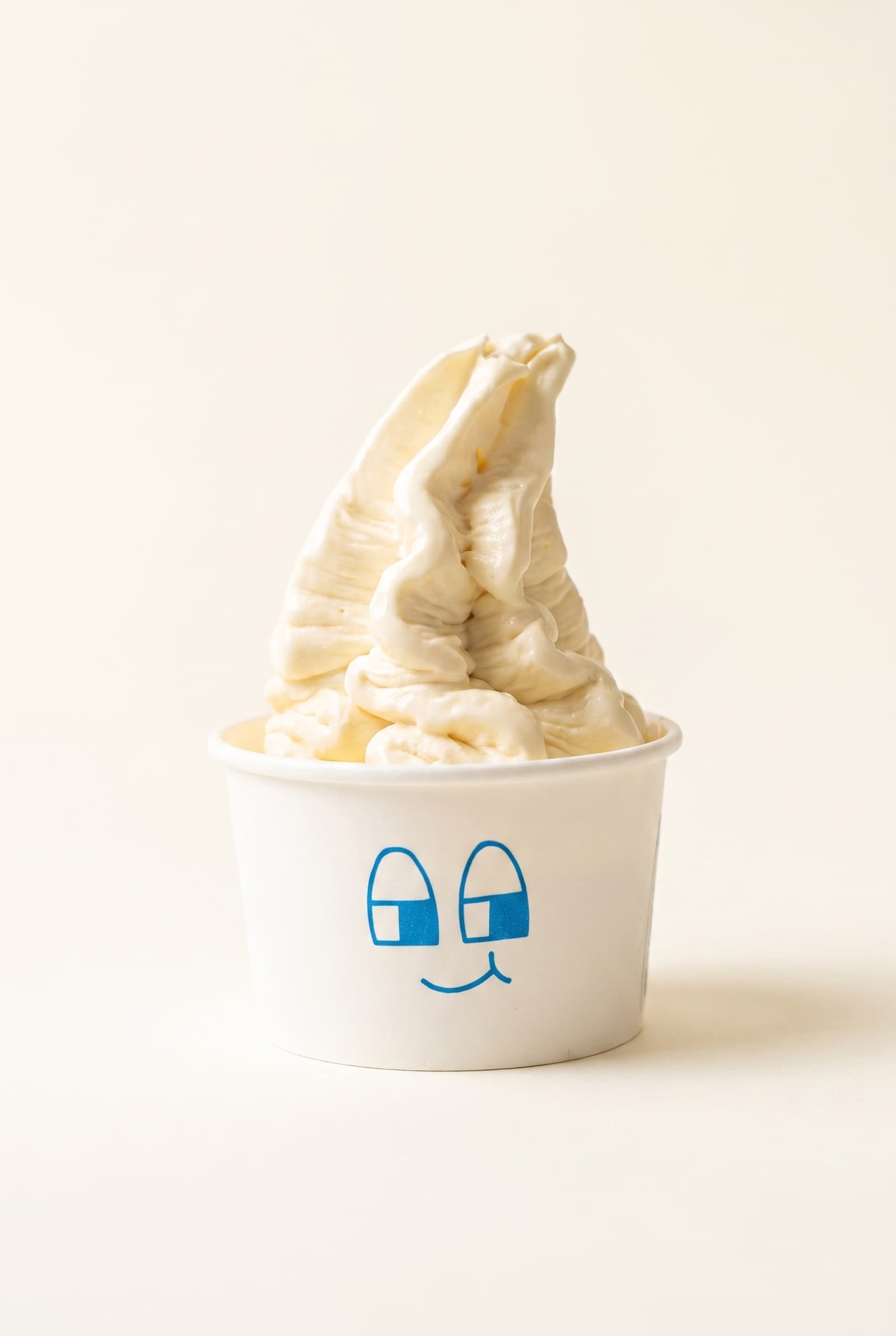 Swirl de yoghurt natural de MILKO en vaso con carita, foto de estudio sobre fondo crema